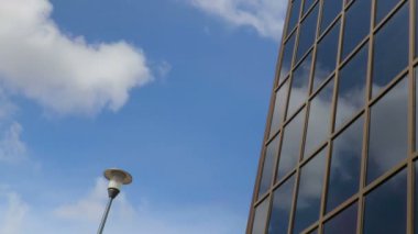 Bina Windows'da yansıyan gökyüzü bulutlar yüzen. Sokak lambası. Hızlandırılmış kayıt.