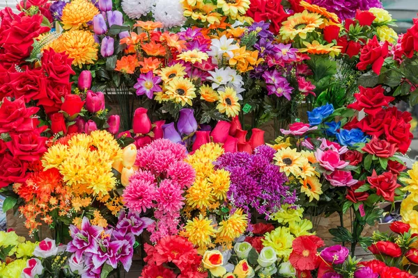 Une variété de fleurs artificielles. Fond coloré de fleurs — Photo