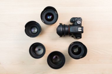 Dijital Slr fotoğraf makinesi ve birkaç değiştirilebilir manuel lensler. Film yapım donatımı. Ahşap masa