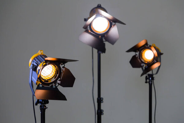 Three halogen spotlights with Fresnel lenses on a grey background. Photographing and filming in the interior. Lighting equipment for movie production