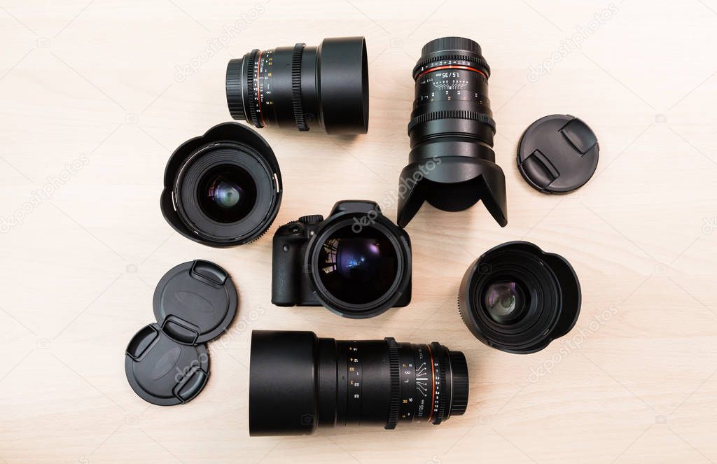 Digital SLR camera and a few interchangeable manual lenses. The equipment for filmmaking. The wooden table