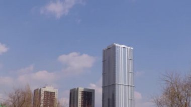 Ağaçlar ve evler gökyüzü. Mavi gökyüzüne çalıştıran bulutlar. Hızlandırılmış kayıt. 4 k, Uhd görüntüleri