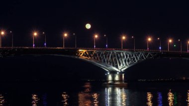 Dolunay üzerinde köprü yükselir. Saratov şehirler ve Engels, Rusya arasındaki yolu köprüsü. Volga Nehri. Arabalar ve sokak ışıkları akşam ışıklar