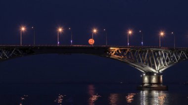 Dolunay üzerinde köprü yükselir. Saratov şehirler ve Engels, Rusya arasındaki yolu köprüsü. Volga Nehri. Arabalar ve sokak ışıkları akşam ışıklar