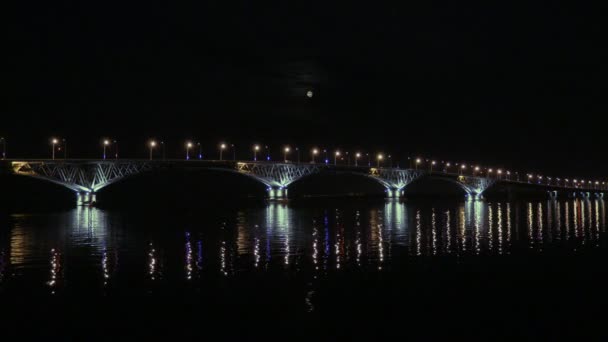 La luna llena se levanta sobre el puente. Puente de carretera entre las ciudades de Saratov y Engels, Rusia. El río Volga. Las luces de la noche de los coches y luces de la calle. 4K, Ultra HD — Vídeo de stock