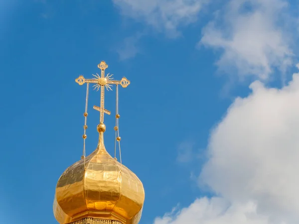 La cupola d'oro di un tempio ortodosso su sfondo di cielo azzurro e nuvole. Croce d'oro sulla cupola del tempio — Foto Stock