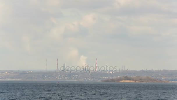 A vista do rio Volga no distrito de Fábrica da cidade de Saratov. A Rússia. Uma paisagem fluvial. Tubo de fábrica. Poluição ambiental, emissões para a atmosfera. O céu e as nuvens. Desfasamento temporal. 4K, UHD, Ultra HD — Vídeo de Stock