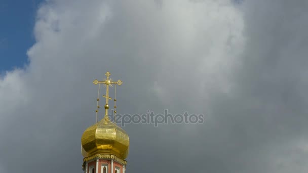Золотой купол православного храма на фоне голубого неба и облаков. Золотой крест на куполе храма. Время истекло. 4K, Ultra HD, UHD — стоковое видео