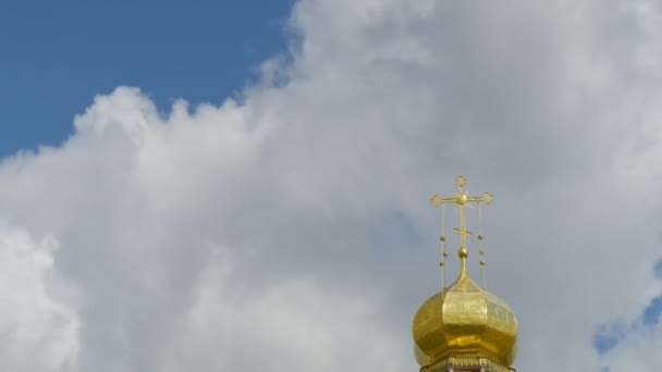 La cúpula dorada de un templo ortodoxo sobre fondo de cielo azul y nubes. Cruz dorada en la cúpula del templo. El lapso de tiempo. Un clip en bucle sin interrupciones. 4K, Ultra HD, UHD — Vídeo de stock