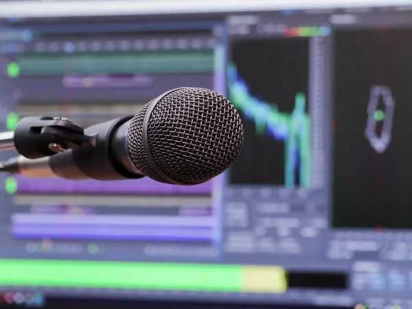 Microphone sur le fond de l'écran de l'ordinateur. Studio d'enregistrement à domicile. Gros plan. Le focus au premier plan. Fond flou. Logiciel pour enregistrer et éditer les sons — Photo