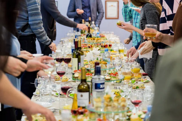 Employees of the company at the Banquet. Table with delicacies, alcohol and snacks. A gala reception. Catering