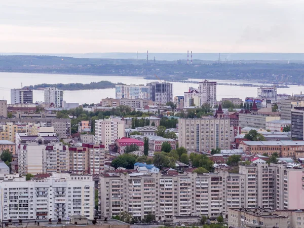 Vista della città di Saratov dalla montagna. Il paesaggio urbano, le infrastrutture, le case popolari, gli edifici pubblici e le strade, il fiume Volga all'orizzonte. Provincia russa — Foto Stock