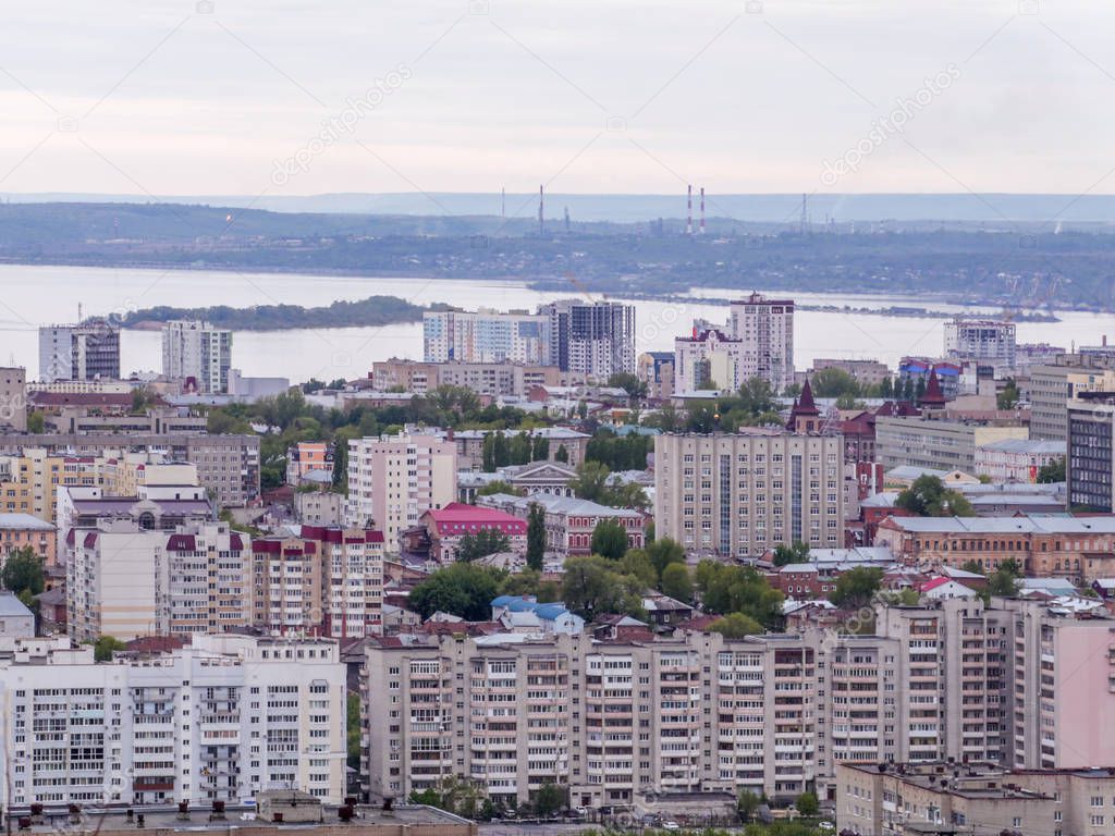 View of the city of Saratov from the mountain. The urban landscape, infrastructure, tenement houses, public buildings and streets, the Volga river on the horizon. Russian province