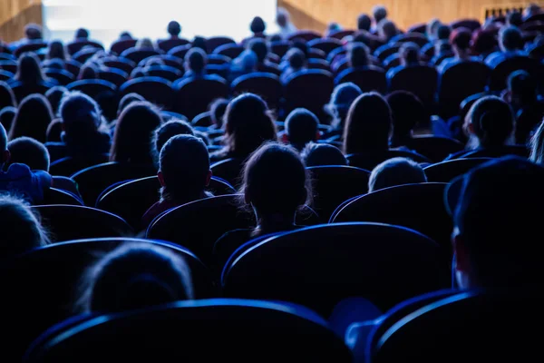 Ludzie, dzieci, dorosłych, rodziców w teatrze oglądania wydajność. Ludzie na widowni, patrząc na stole montażowym. Strzelanie z tyłu — Zdjęcie stockowe