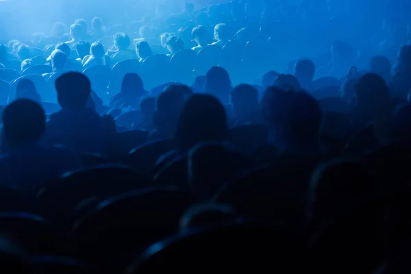 People, children, adults, parents in the theater watching the performance. People in the auditorium looking at the stage. Shooting from the back — Stock Photo, Image