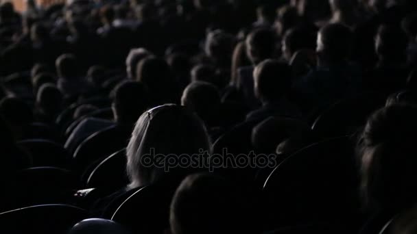 Die Zuschauer schauen sich die Show an oder schauen sich im Theater um. Video von der Rückseite. Kinder und Erwachsene gleichermaßen — Stockvideo