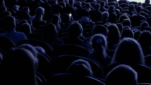 Los espectadores ven el espectáculo o la vista en el teatro. Vídeo de atrás. Niños y adultos por igual. Imágenes de clip en 4K — Vídeo de stock