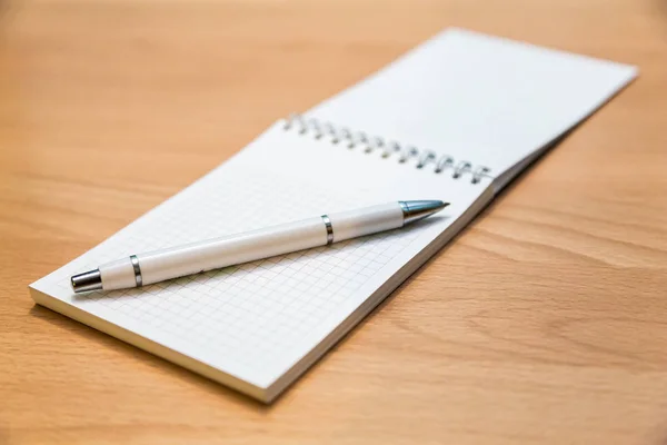 Un cuaderno y un bolígrafo sobre una mesa de madera —  Fotos de Stock