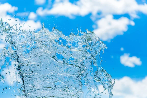 Vattenstänk mot en blå himmel och moln — Stockfoto