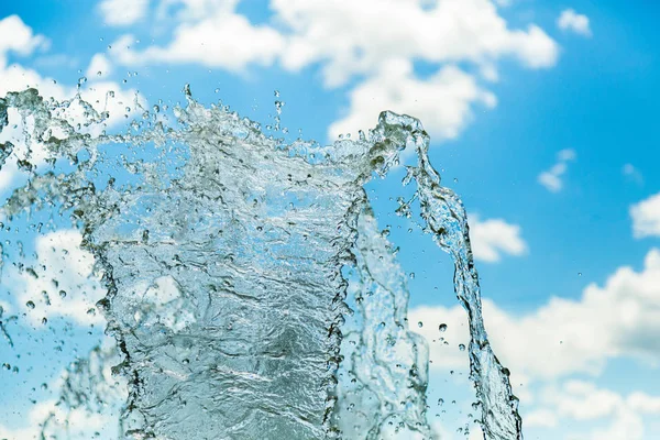 Vattenstänk mot en blå himmel och moln — Stockfoto
