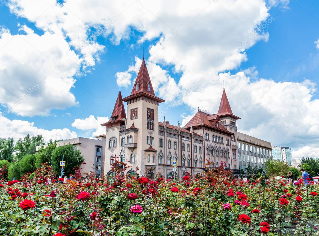 Saratov State Conservatoire. Was opened in 1912. Russia. Blooming roses in the foreground. Clouds on a blue sky