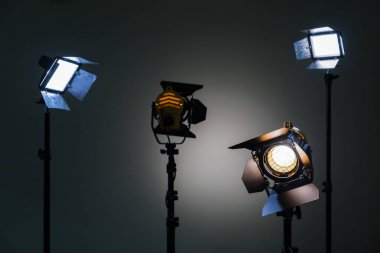 Two floodlights with halogen lamps and Fresnel lens and two led lighting device. Shooting in the interior on a gray background clipart