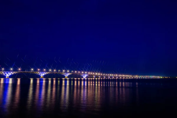 Straßenbrücke über die Wolga zwischen den Städten Saratow und Engels, Russland. Nacht- oder Abendlandschaft. Goldene Straßenlaternen. die Spiegelung im Wasser — Stockfoto