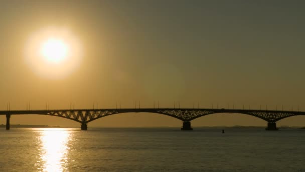 Salida del sol sobre un puente de carretera a través del río Volga, Rusia. El puente entre las ciudades de Saratov y Engels. Mañana de verano. Clip de vídeo 4k — Vídeo de stock
