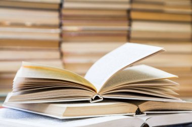 Renkli kapaklı kitap yığını. Kitaplık veya kitapçı. Kitap veya ders kitapları. Eğitim ve okuma. Ön planda açık kitap