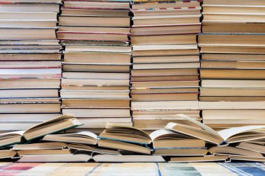Renkli kapaklı kitap yığını. Kitaplık veya kitapçı. Kitap veya ders kitapları. Eğitim ve okuma. Ön planda açık kitap