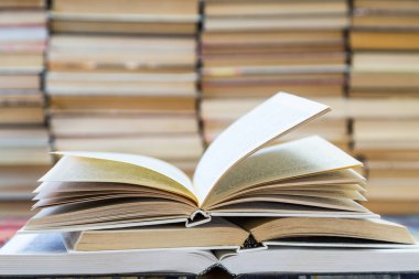 Renkli kapaklı kitap yığını. Kitaplık veya kitapçı. Kitap veya ders kitapları. Eğitim ve okuma. Ön planda açık kitap
