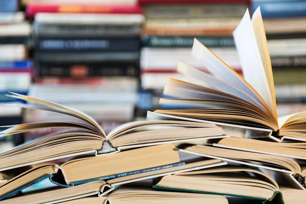 Renkli kapaklı kitap yığını. Kitaplık veya kitapçı. Kitap veya ders kitapları. Eğitim ve okuma. Ön planda açık kitap