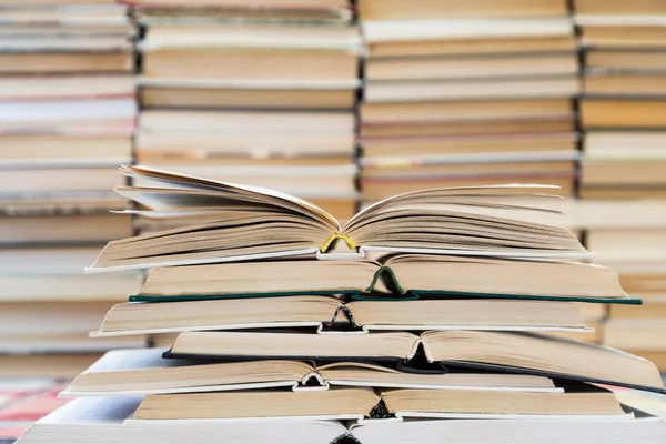 Renkli kapaklı kitap yığını. Kitaplık veya kitapçı. Kitap veya ders kitapları. Eğitim ve okuma. Ön planda açık kitap