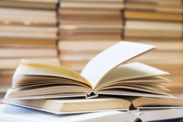 Renkli kapaklı kitap yığını. Kitaplık veya kitapçı. Kitap veya ders kitapları. Eğitim ve okuma. Ön planda açık kitap