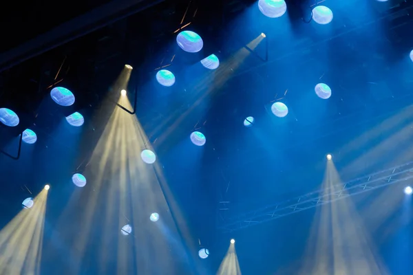Sprzęt oświetleniowy na scenie teatru podczas występu. Promienie światła z reflektora przez dym. Niebieskie i żółte promienie światła — Zdjęcie stockowe