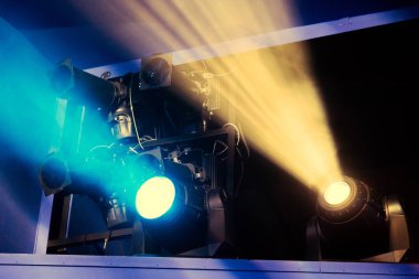 Lighting equipment on the stage of the theatre during the performance. The light rays from the spotlight through the smoke. Blue and yellow rays of light clipart