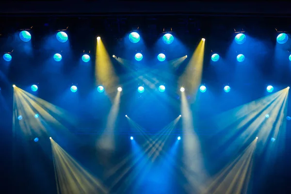 Equipamento de iluminação no palco do teatro durante a apresentação. Os raios de luz do holofote através da fumaça. Raios de luz azuis e amarelos — Fotografia de Stock