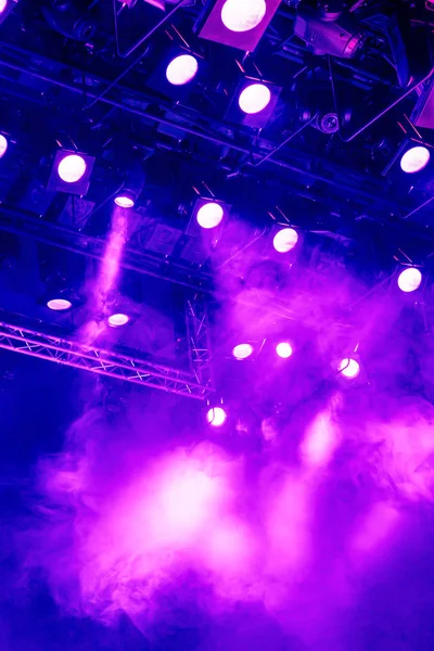Lila Lichtstrahlen aus dem Scheinwerferlicht durch den Rauch im Theater oder Konzertsaal. Beleuchtungsanlagen für eine Vorstellung oder Show — Stockfoto