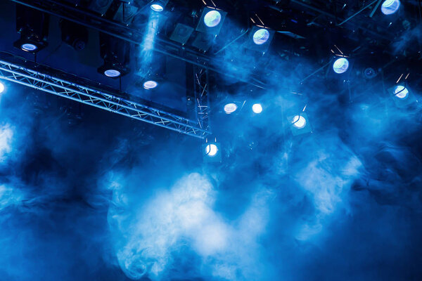 Blue light rays from the spotlight through the smoke at the theater or concert hall. Lighting equipment for a performance or show