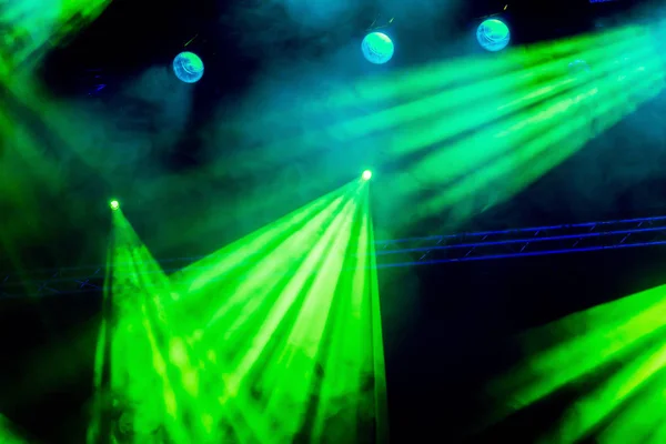 Grüne Lichtstrahlen aus dem Scheinwerferlicht durch den Rauch im Theater oder Konzertsaal. Beleuchtungsanlagen für eine Vorstellung oder Show — Stockfoto