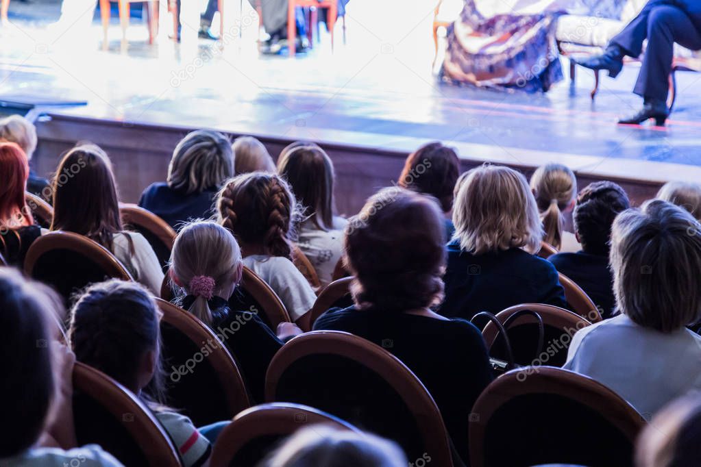 The audience in the theater watching a play. The audience in the hall: adults and children