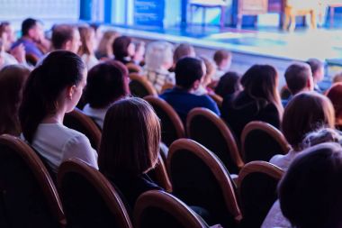 Seyirciler bir oyun izlerken tiyatro. Seyirciler salonda: yetişkinler ve çocuklar.