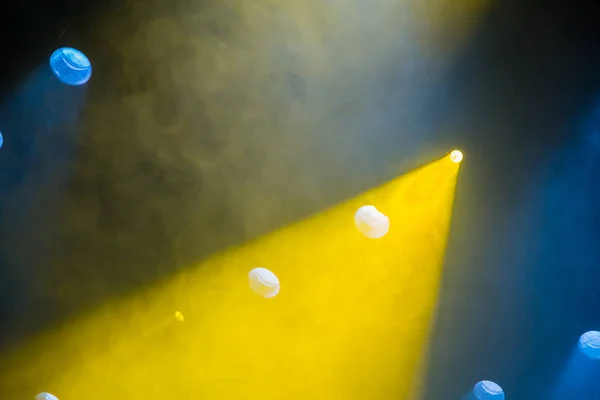Žluté a modré paprsky světla z reflektorů prostřednictvím divadelní dým. Osvětlovací zařízení na jevišti — Stock fotografie