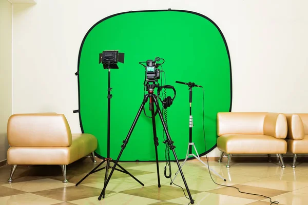 La fotocamera sul treppiede, proiettore a led, cuffie e un microfono direzionale su sfondo verde. La chiave cromatica. Schermo verde — Foto Stock