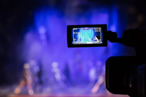 Filming the show from the auditorium. LCD viewfinder on the camcorder. Theatrical performance. The actors on stage. Out-of-focus background. The focus in the foreground.