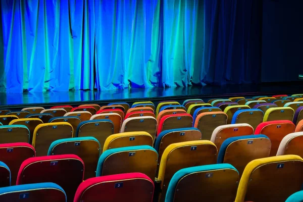 剧院的礼堂舞台上的蓝绿色窗帘 多彩多姿的观众的椅子 照明设备 — 图库照片