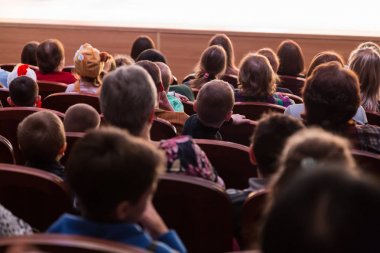 İnsanlar, bir çocuk programı izlerken seyirciler çocuklu anne. Sattı. Arkadan çekim.