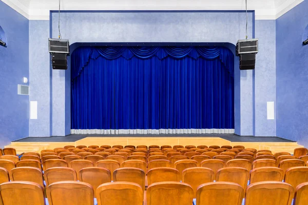The auditorium in the theater. Blue curtain on the stage. Blue-brown chair. Room without people.