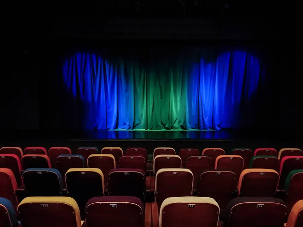剧院的礼堂舞台上的蓝绿色窗帘 多彩多姿的观众的椅子 照明设备 — 图库照片