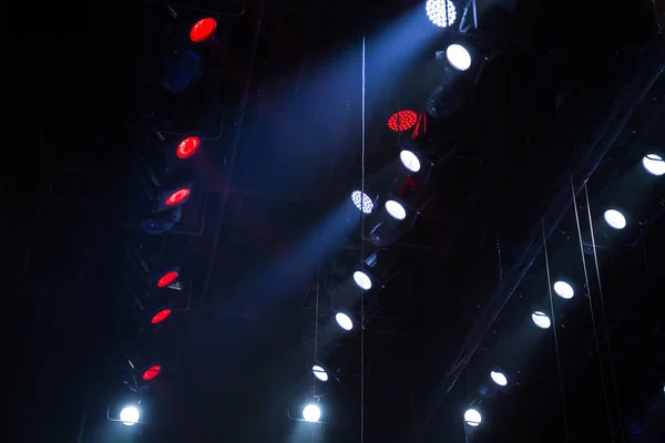 Lighting equipment on the stage of a theatre or concert hall. The rays of light from spotlights. Halogen and led light bulbs. Lens lighting.